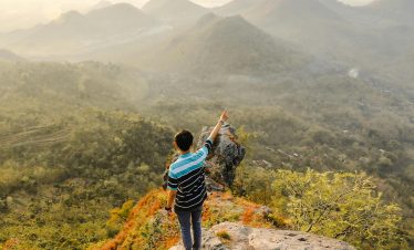 Man pointing at scenic Mandau Talawang mountains, Central Kalimantan, Indonesia.